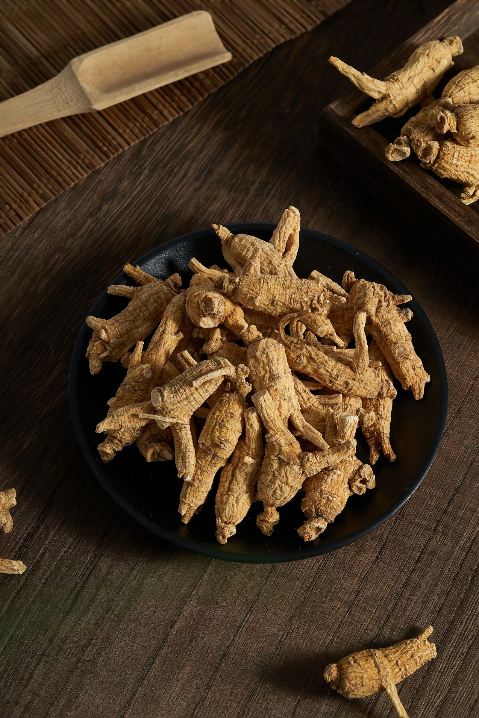 Dried roots in a dark bowl on natural wood.